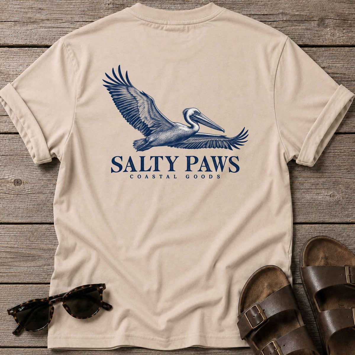 Gliding Pelican Coastal Goods Back Design T-Shirt in Sand, Salty Paws T-Shirt, back design flat lay