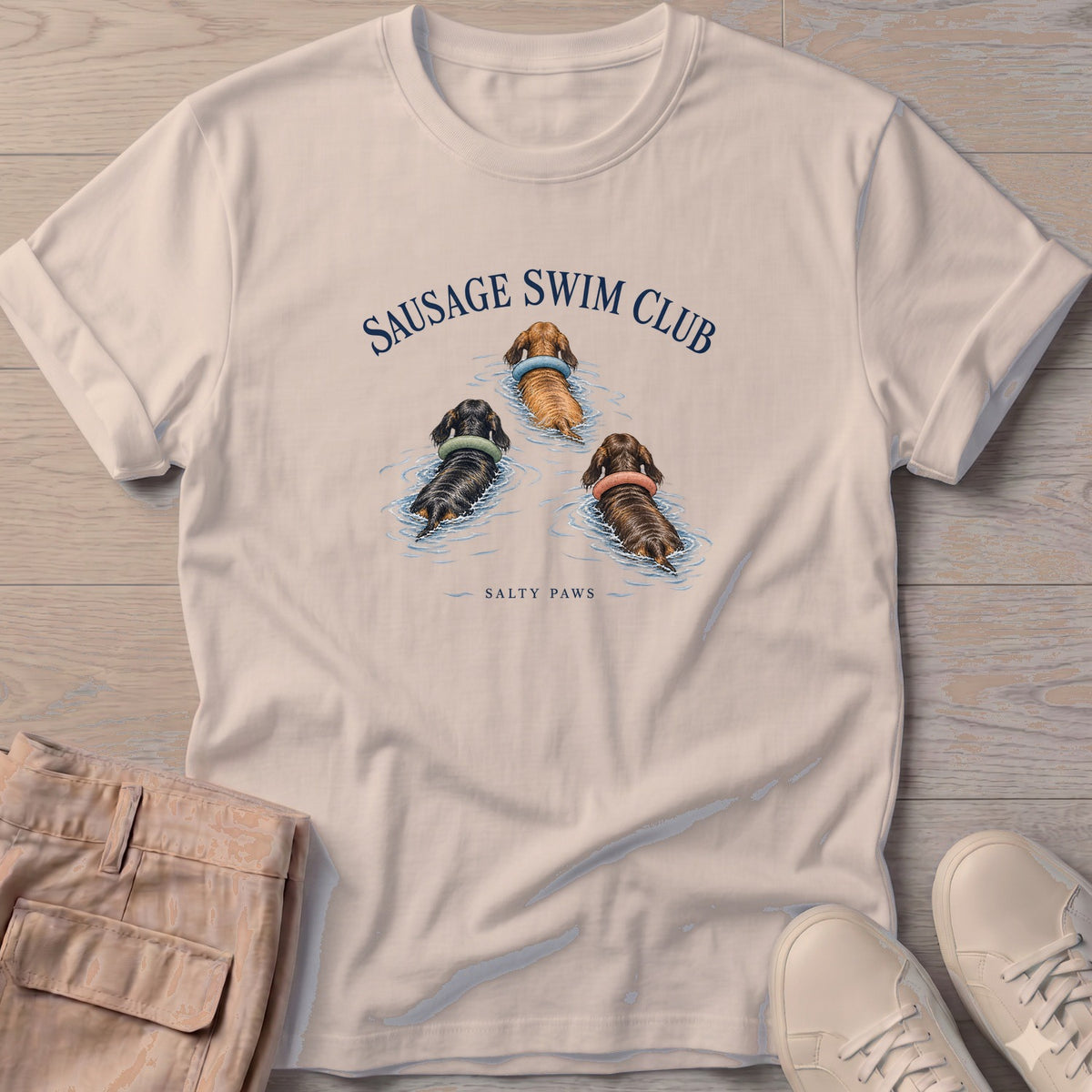 Sausage Swim Club Dachshund Trio T-Shirt in Sand, Salty Paws T-Shirt, front design flat lay